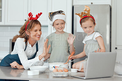 Buy stock photo Shot of a grandmother and her two granddaughters having a video call on a laptop while baking together at home
