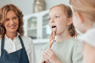 Buy stock photo Shot of a little girl licking a wooden spoon while baking with her sister and grandmother at home
