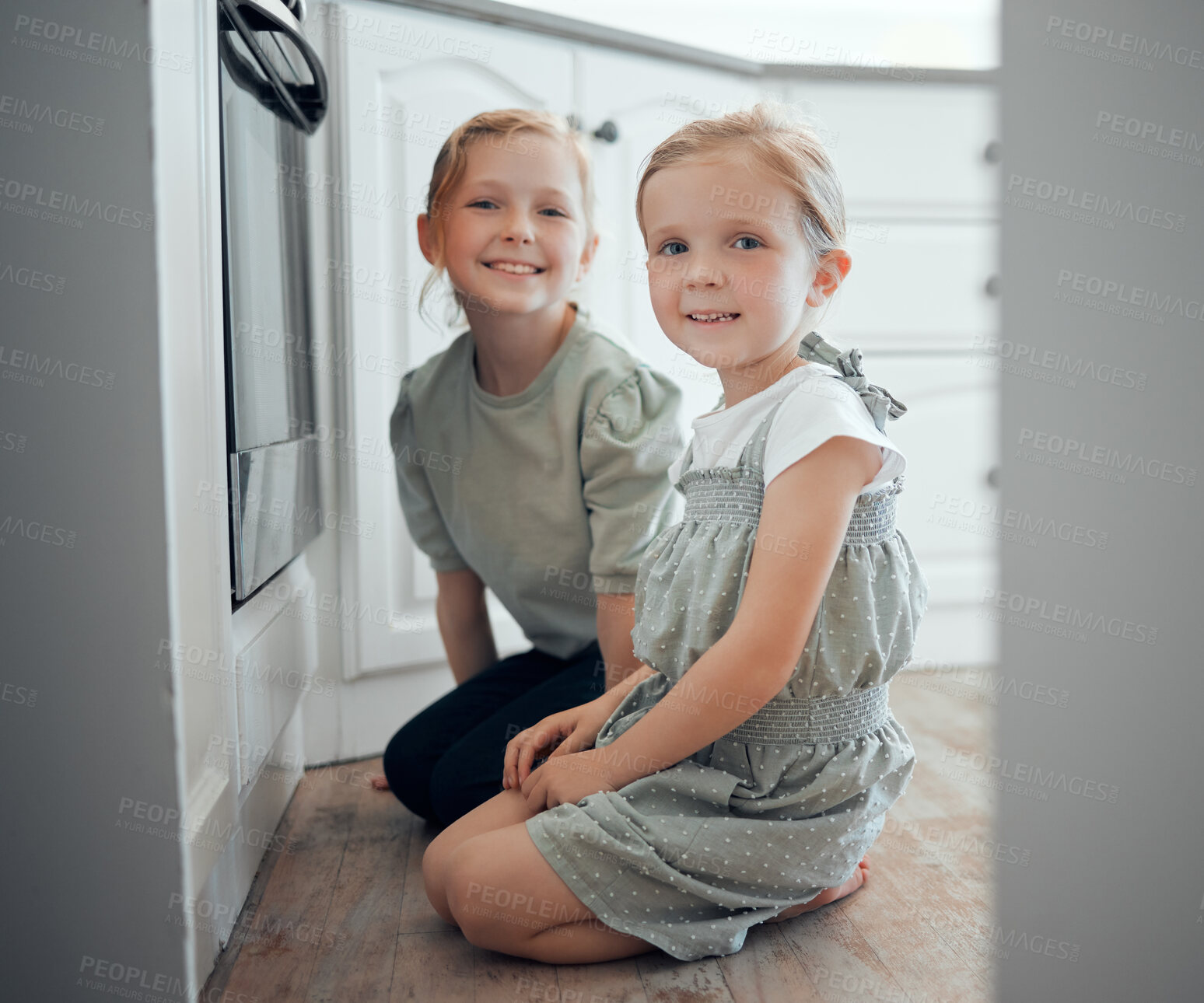 Buy stock photo Girl, children and portrait by oven in kitchen on floor with excitement for baking, cooking and growth or development. Female kids, siblings and together on ground in house for observe and patience.