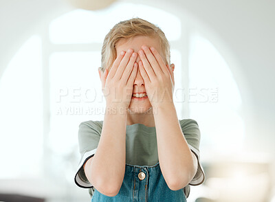 Buy stock photo Shot of an adorable little girl standing alone at home and covering her eyes with her hands
