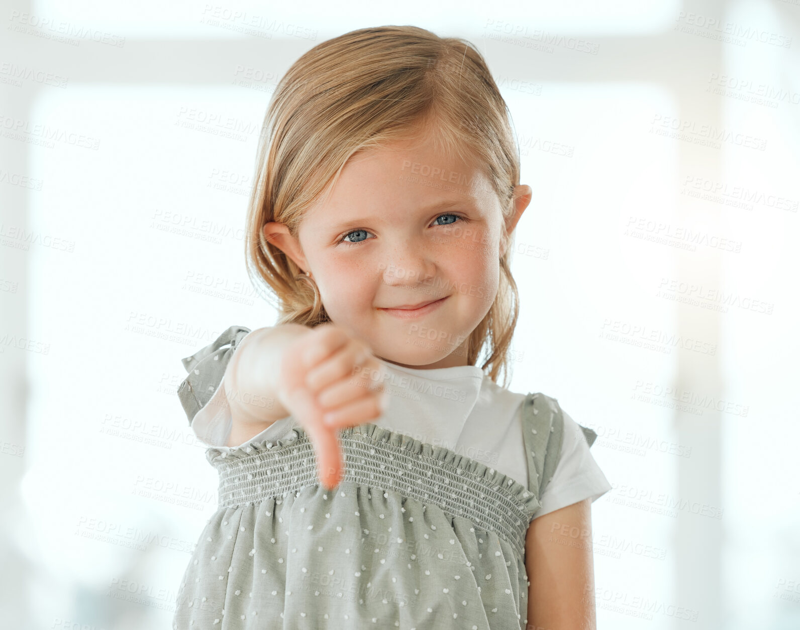 Buy stock photo Girl, portrait and thumbs down in home for dislike, opinion and fail with rejection, review and feedback. Female child, face and choice for disappointed, vote and decision with negative emoji sign