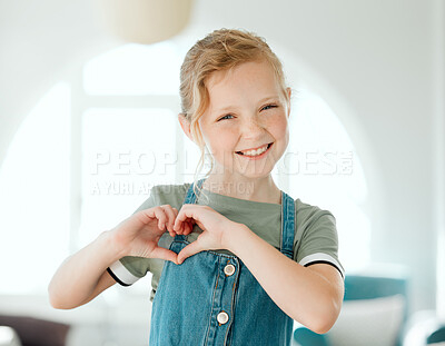 Buy stock photo Shot of an adorable little girl standing alone at home and making a heart sign gesture