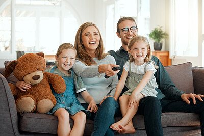 Buy stock photo Shot of a young family sitting on the sofa at home and bonding while watching television