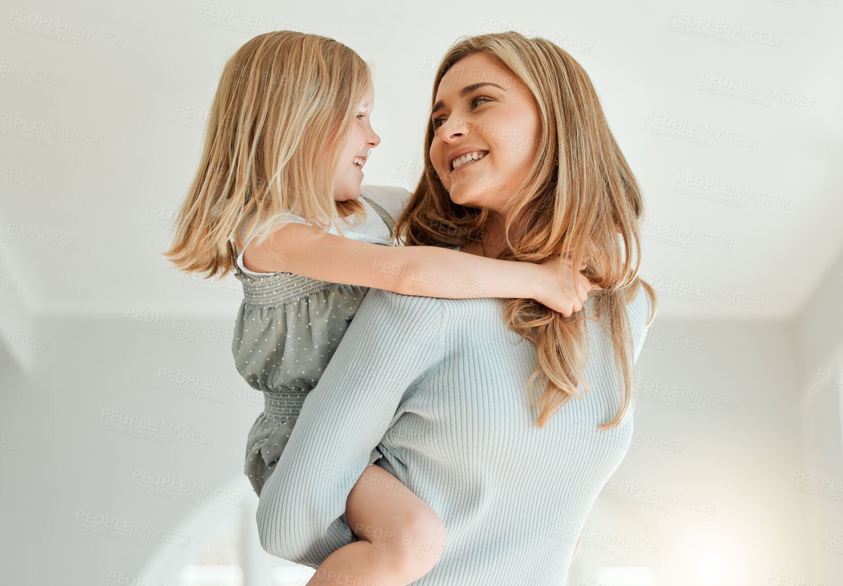 Buy stock photo Shot of an attractive young woman bonding with her daughter and giving her a piggyback ride at home