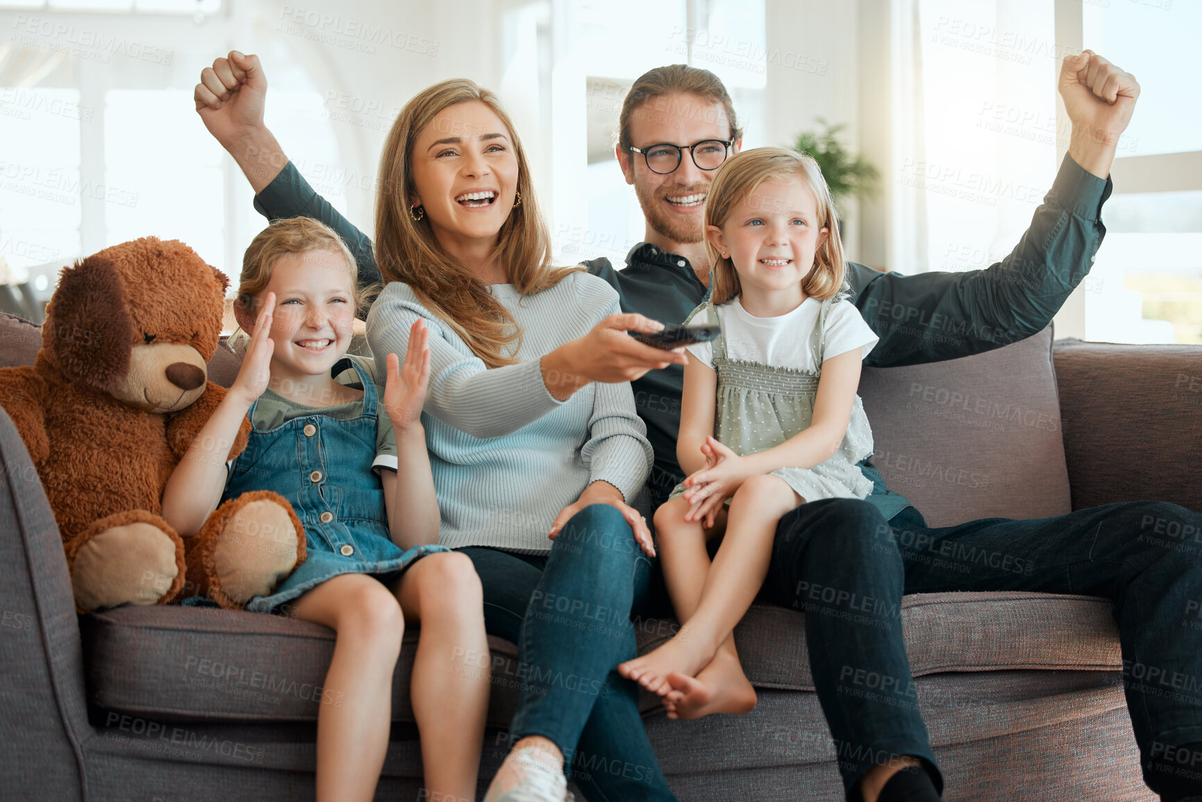 Buy stock photo Shot of a young family sitting on the sofa at home and bonding while watching television