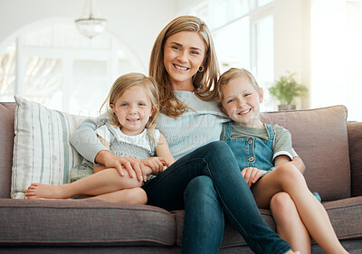 Buy stock photo Shot of two adorable little girls sitting on the sofa and bonding with their mother at home