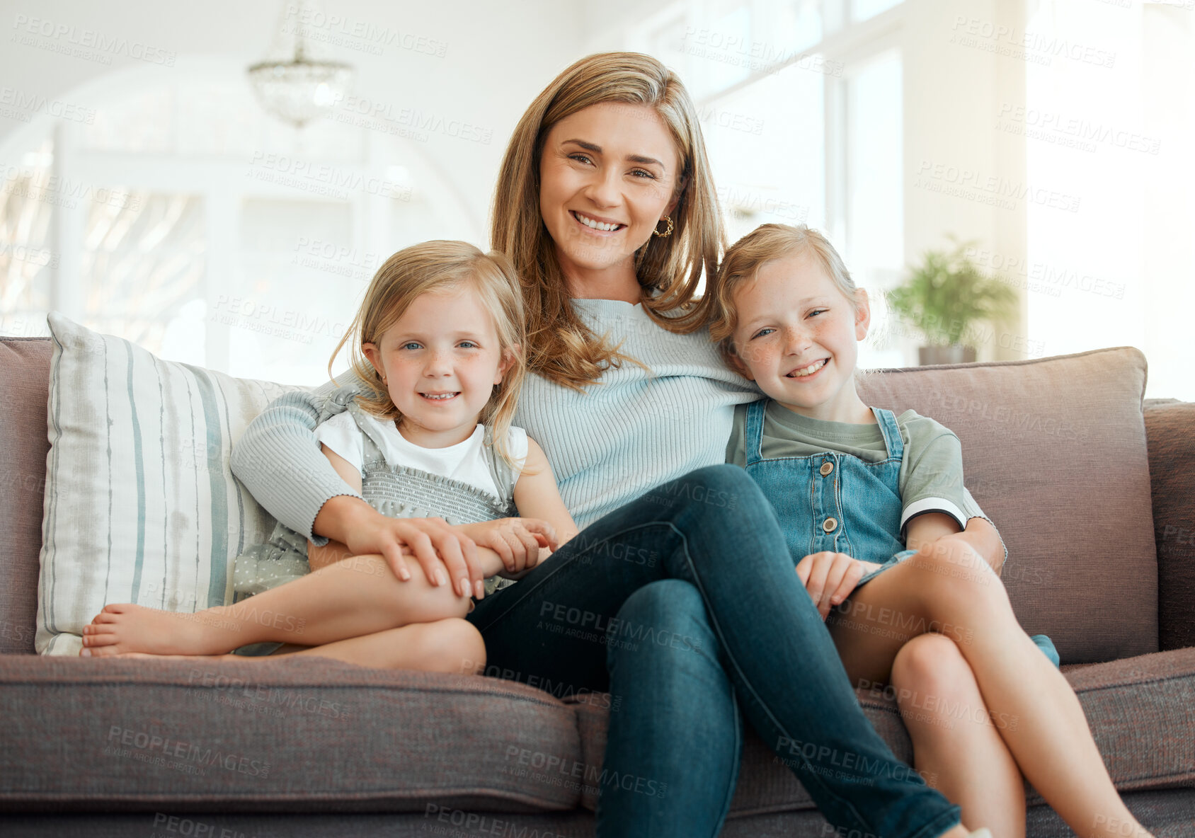 Buy stock photo Shot of two adorable little girls sitting on the sofa and bonding with their mother at home