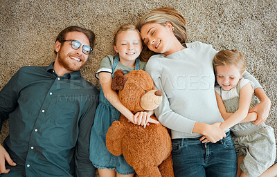 Buy stock photo High angle shot of a young family lying together on the living room floor at home
