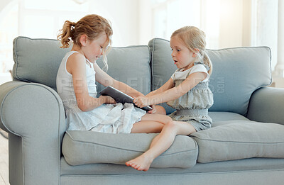 Buy stock photo Shot of two little girls fighting over a digital tablet on a sofa at home