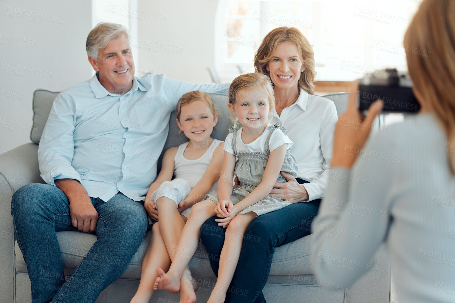 Buy stock photo Grandparents, girls and happy with photographer on sofa at home for bonding, support and care. People, family and smile with kids on couch in living room to relax or chill for child development