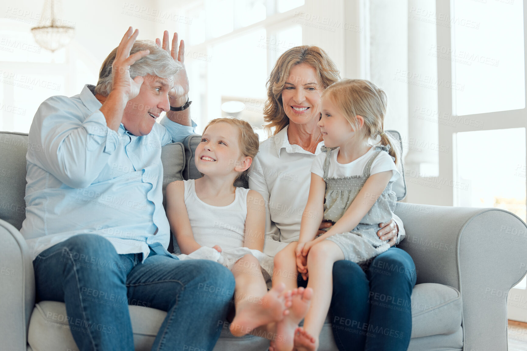 Buy stock photo Bunny ears, smile or visit with grandparents and children on sofa in living room of home together. Having fun, laughing or joking with senior man, woman and sister girls in apartment for comedy