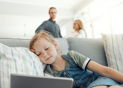 Buy stock photo Shot of a little girl using a digital tablet while her parents argue in the background at home