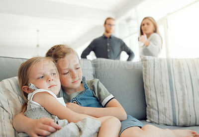 Buy stock photo Shot of two little girls holding each other while their parents argue in the background at home