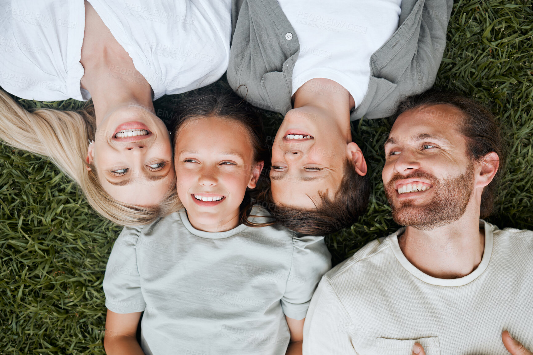 Buy stock photo Grass, laughing and smile of parents with children outdoor on lawn together for family bonding. Face, funny or wellness with happy mother, father and sibling kids in backyard of home from above