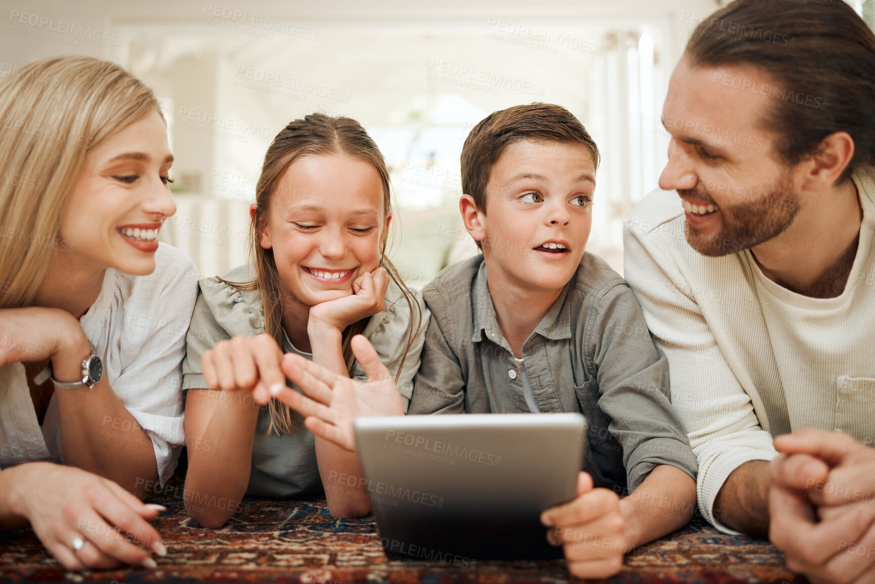 Buy stock photo Shot of a young family spending time together at home while using a digital tablet