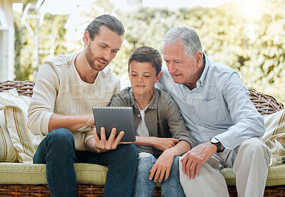 Buy stock photo Shot of a man using a digital tablet while sitting outside with son and his elderly father