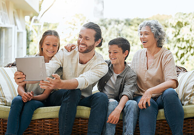 Buy stock photo Shot of a man using a digital tablet while sitting outside with his children and their grandmother
