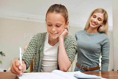 Buy stock photo Shot of a mother helping her daughter with homework at the kitchen table at home