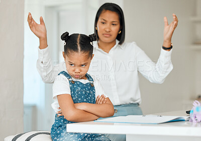 Buy stock photo Shot of a young mother looking frustrated while helping her daughter with homework at home