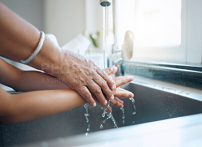 Buy stock photo Shot of a senior woman and a child washing their hands in the kitchen sink