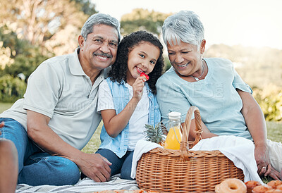 Buy stock photo Shot of grandparents enjoying a  picnic with their granddaughter outside
