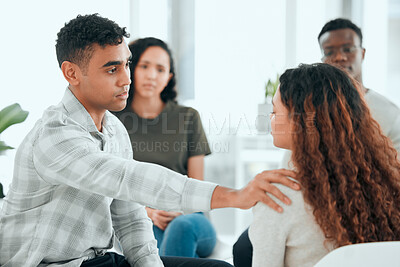 Buy stock photo Shot of a handsome young man sitting and comforting a member of his support group
