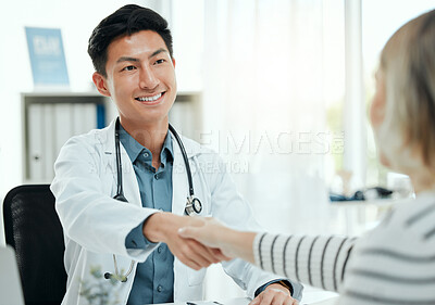 Buy stock photo Shot of a mature doctor sitting in the clinic and shaking hands with his patient