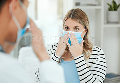 Buy stock photo Shot of two people putting on a mask in a clinic