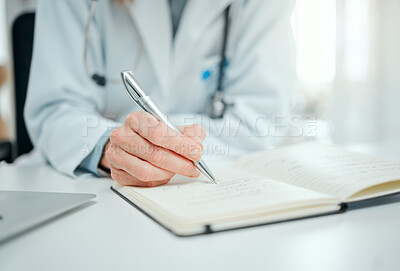 Buy stock photo Cropped shot of an unrecognisable doctor sitting alone in her clinic and writing notes