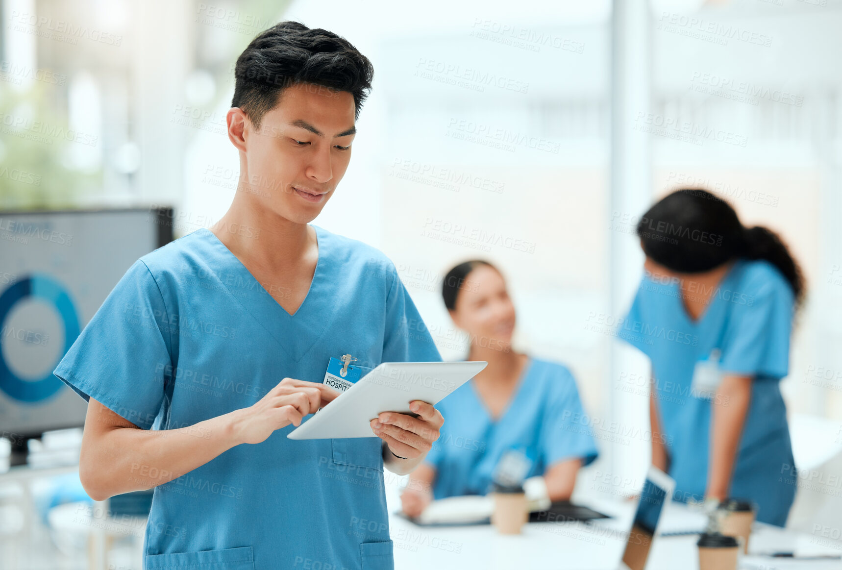 Buy stock photo Shot of a young male doctor using a digital tablet at a hospital