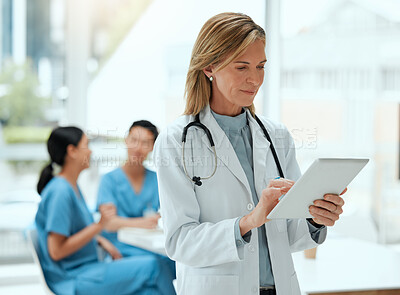 Buy stock photo Shot of a mature female doctor using a digital tablet at a hospital