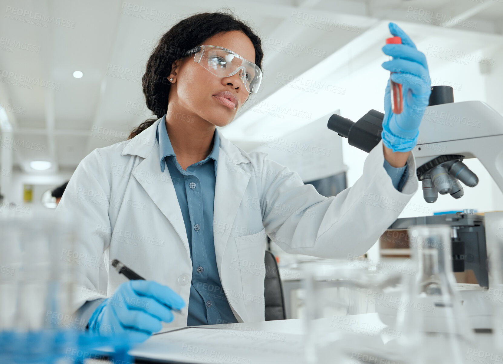Buy stock photo Shot of a young woman reviewing a test tube sample in the lab