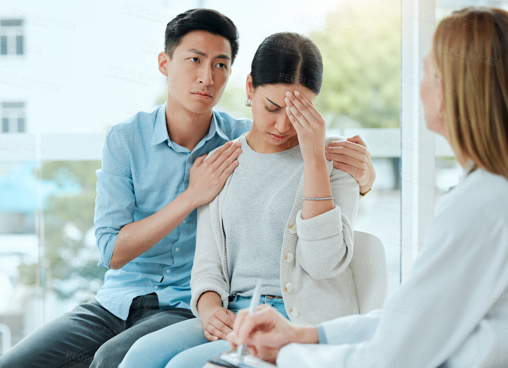 Buy stock photo Shot of a mature doctor comforting a young couple while delivering some bad news at work