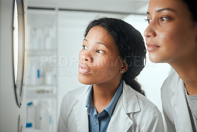 Buy stock photo Shot of two female scientists looking through a door waiting for results