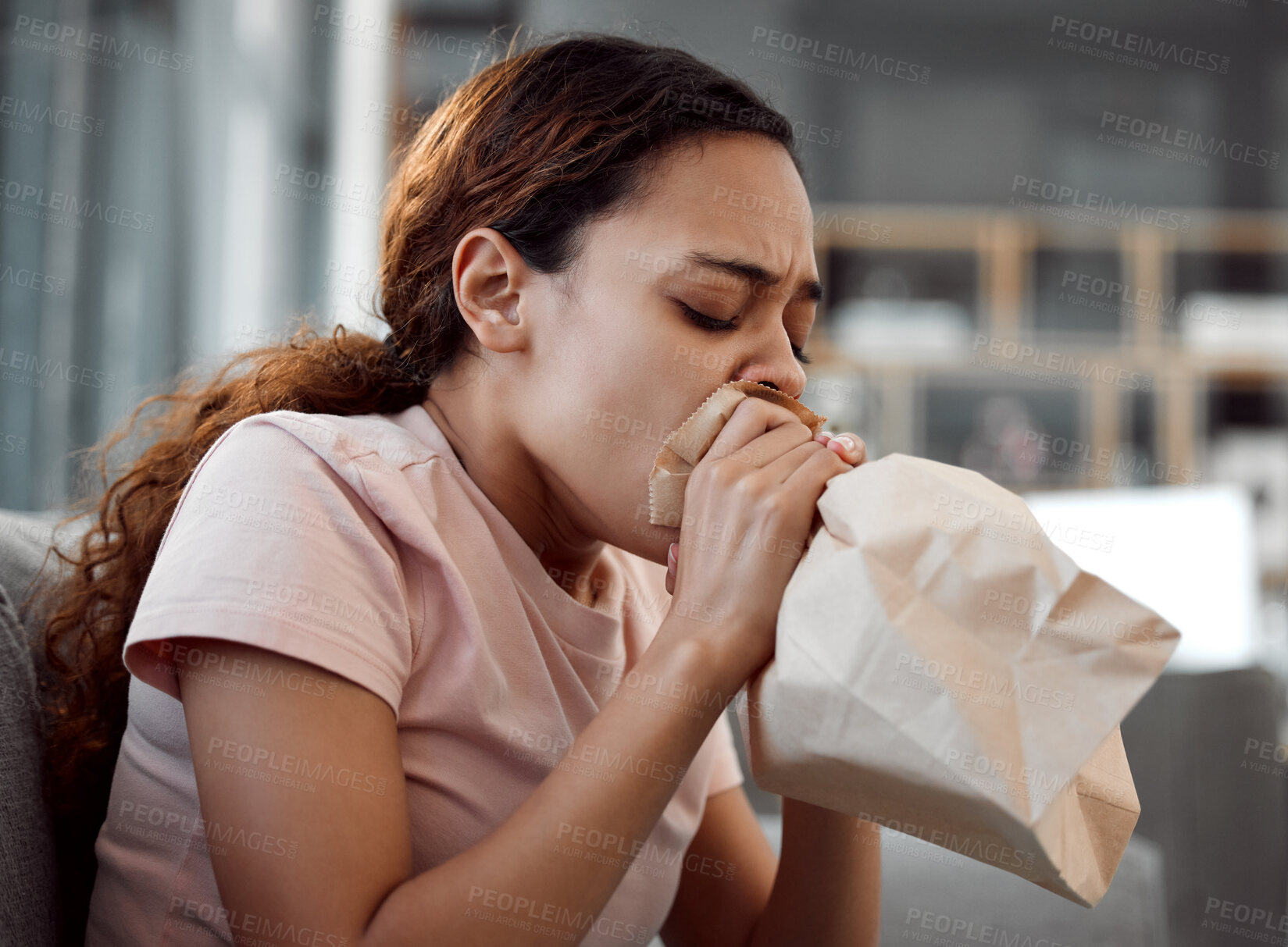 Buy stock photo Shot of a young woman experiencing a panic attack while sitting on the sofa at home