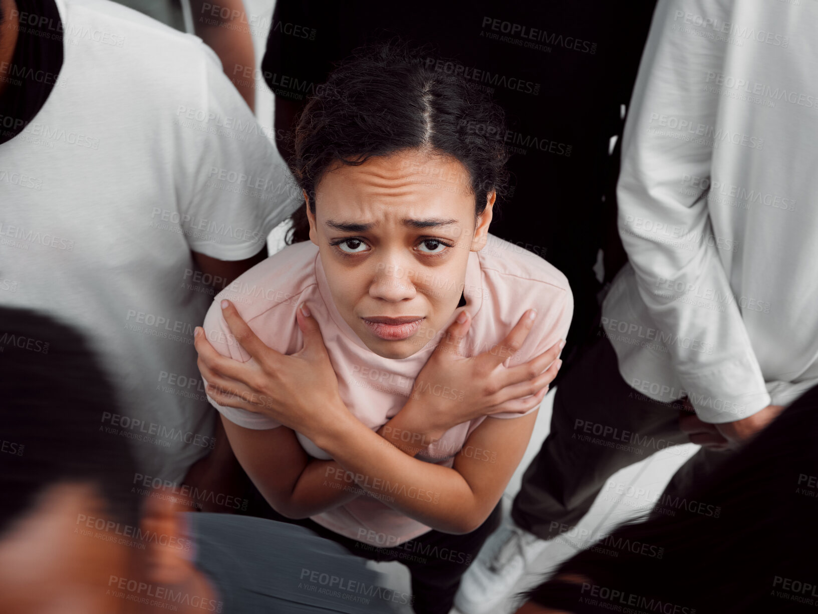 Buy stock photo Shot of a young woman experiencing mental illness while being surrounded by people inside