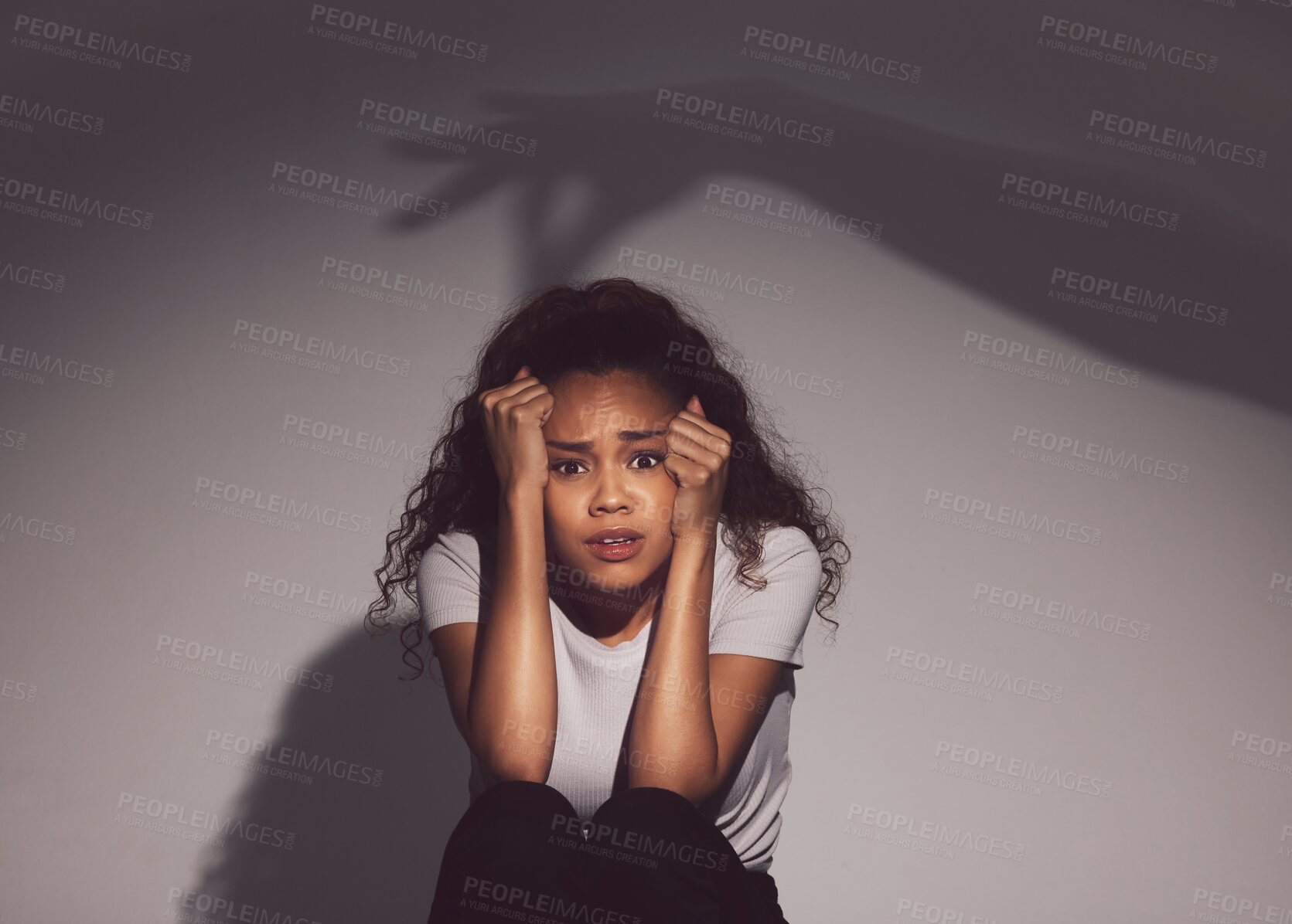 Buy stock photo Frustrated woman, portrait and fear with shadow in trauma, stress or anxiety for mental illness on a studio background. Young, female person or victim with depression in terror for abuse or danger