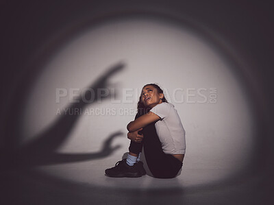 Buy stock photo Scared woman, fear and trauma with shadow or silhouette in stress or anxiety for mental illness on a studio background. Young, female person or victim with depression in terror for abuse or danger