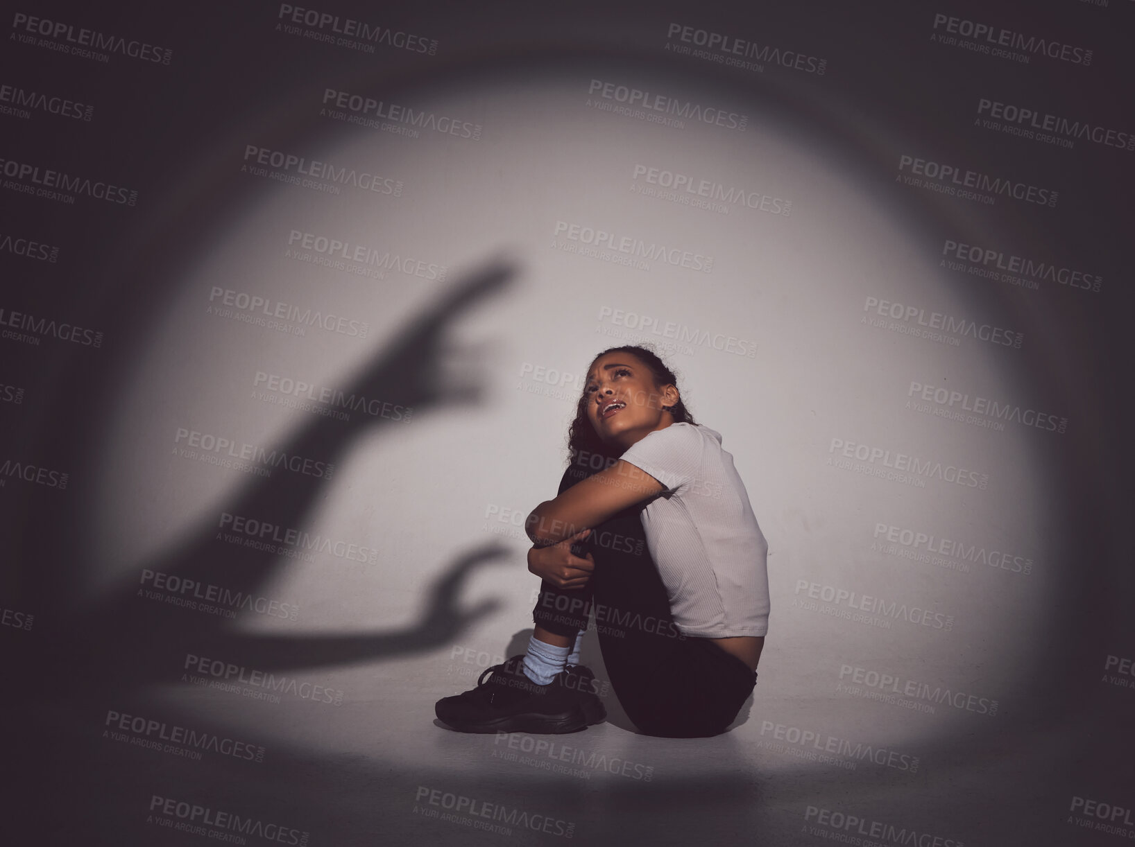 Buy stock photo Scared woman, fear and trauma with shadow or silhouette in stress or anxiety for mental illness on a studio background. Young, female person or victim with depression in terror for abuse or danger