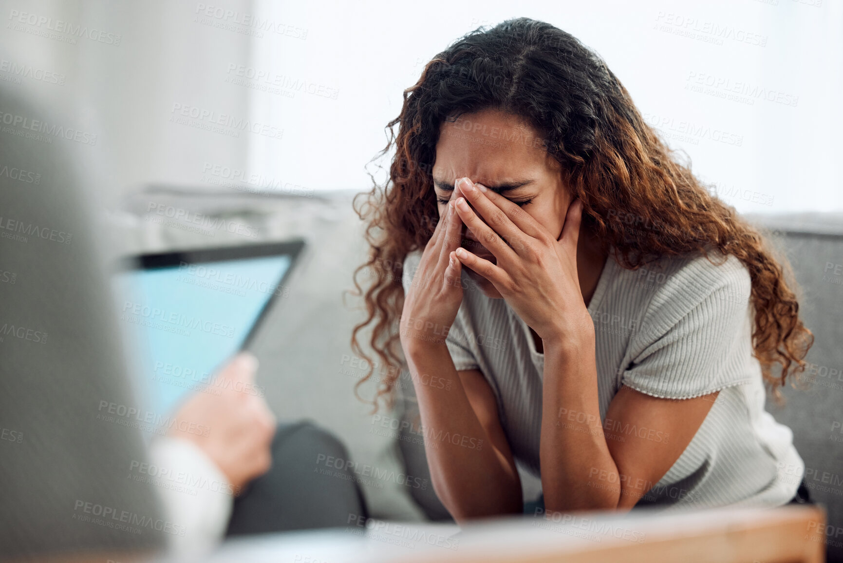 Buy stock photo Shot of an attractive young woman sitting and feeling stressed during her consultation with her psychologist