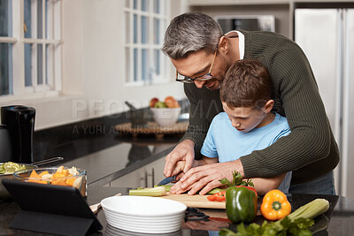 Buy stock photo Shot of a little boy cooking with his father at home