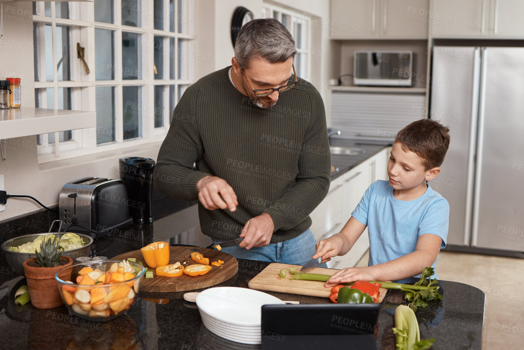 Buy stock photo Father, cooking and child with learning in kitchen for knife skills, cutting vegetables or culinary development. Man, boy kid or support in home with meal preparation, teaching vegan recipe or how to
