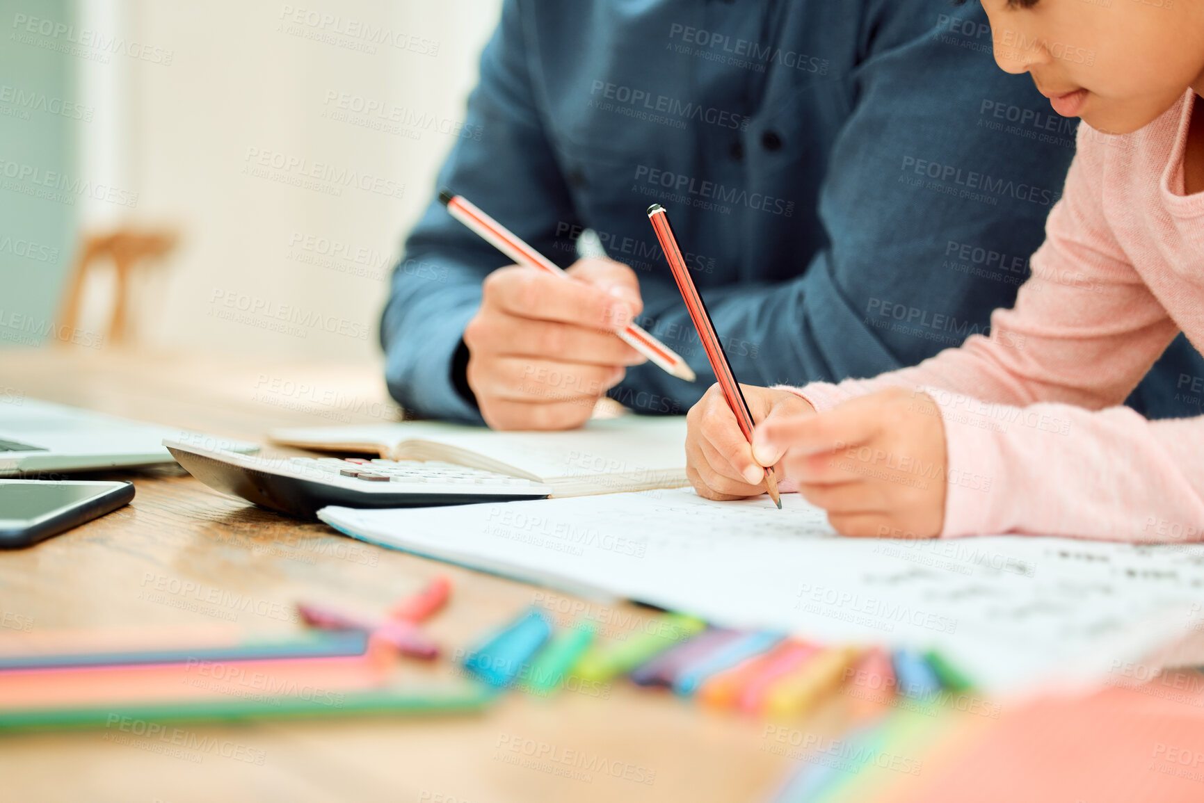Buy stock photo Cropped shot of an unrecognizable little girl doing her homework with some help from her dad