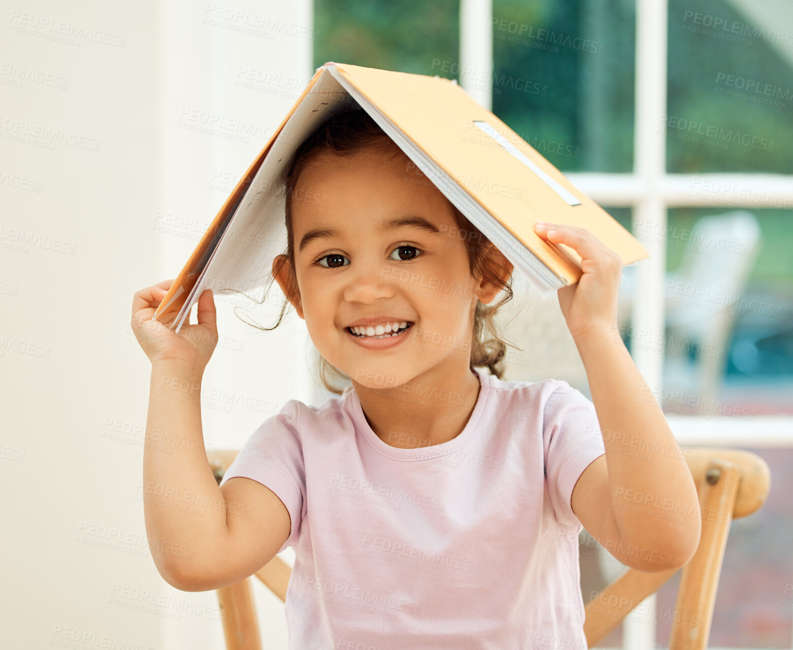 Buy stock photo Cropped portrait of an adorable little girl messing around with her textbook while doing her homework