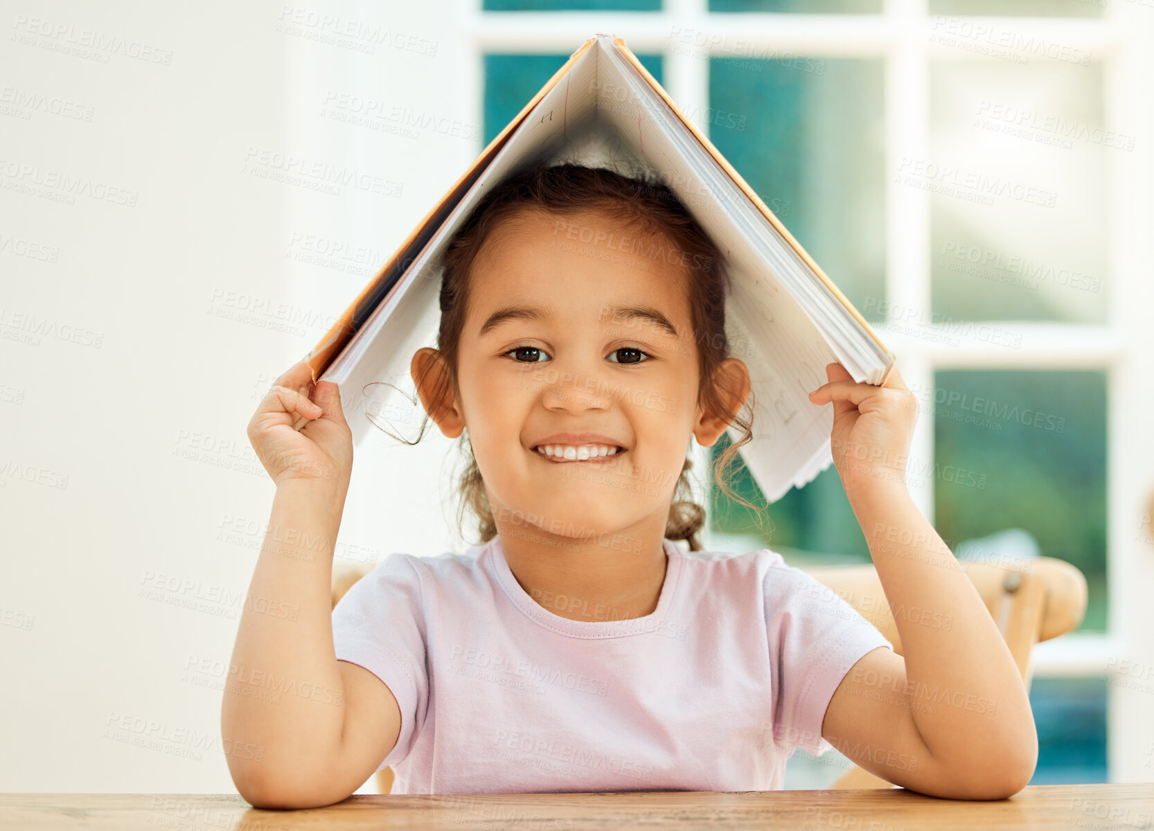 Buy stock photo Cropped portrait of an adorable little girl messing around with her textbook while doing her homework