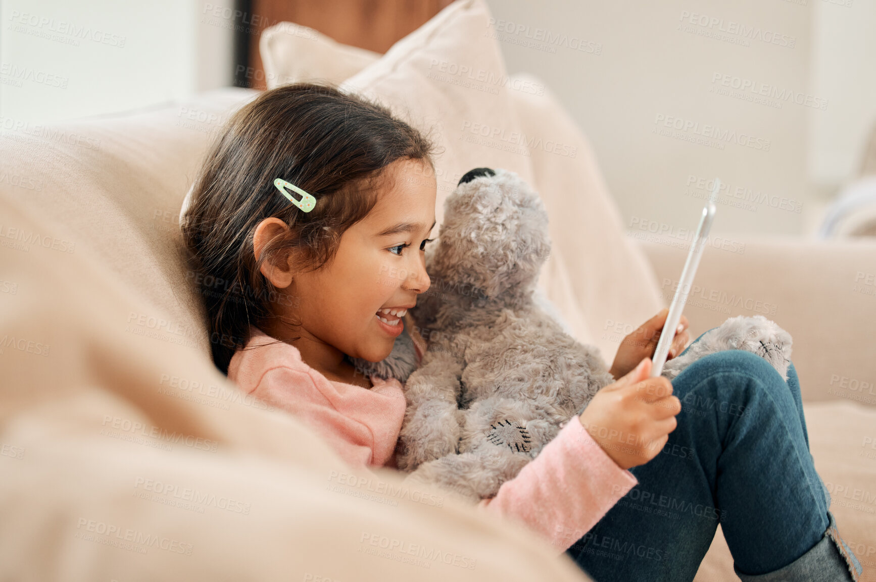 Buy stock photo Kid, girl and happy with tablet on sofa at home on streaming platform for cartoon and movies. Female person, couch and smile or excited in living room with teddy bear on education games for growth