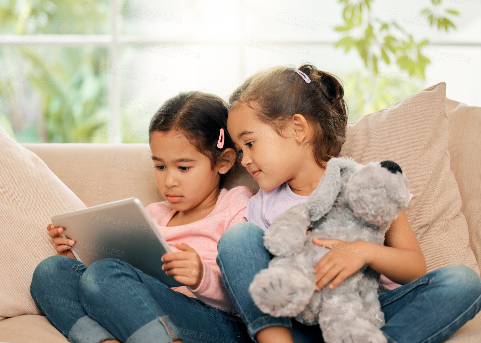 Buy stock photo Kids, sisters and happy with tablet on sofa at home on streaming platform for cartoon and movies. Girls, couch and smile in living room with teddy bear on education games for growth and development