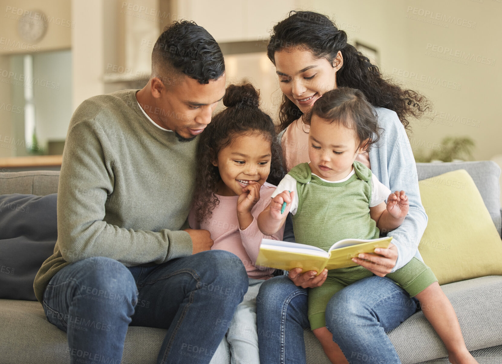 Buy stock photo Shot of a young family bonding while reading a book together at home