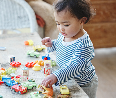 Buy stock photo Shot of an adorable little girl playing with her toys at home