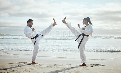 Buy stock photo Full length shot of two young martial artists practicing karate on the beach